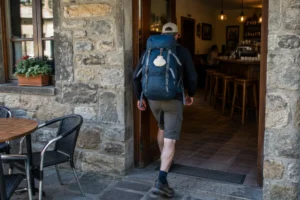 Peregrino entrando em bar de vilarejo, onde costuma usar os banheiros no Caminho de Santiago