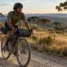 Ciclista com bicicleta gravel equipada com bolsas de bikepacking em estrada de cascalho no campo