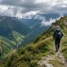 Peregrino com bastões em trilha de cumeada nas montanhas verdes das Astúrias no Caminho Primitivo
