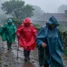 Peregrinos de capa caminhando sob chuva forte na Galícia, no Caminho de Santiago