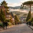 Rua de paralelepípedos com casas em estilo enxaimel, araucárias e hortênsias, em ilustração da Serra Gaúcha