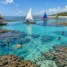 Piscinas naturais de águas azul-turquesa entre arrecifes, com jangadas coloridas e coqueiros
