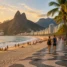 Orla de praia com calçadão de pedras portuguesas, coqueiros e montanhas ao fundo no Rio de Janeiro