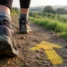 Bota dando um passo sobre seta amarela, o primeiro passo do peregrino