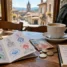 Credencial do peregrino com carimbos, euros e caderno de orçamento sobre mesa de café no Caminho de Santiago