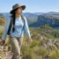 Trilheira de manga longa com proteção UV e calça de trekking caminhando em campo de altitude