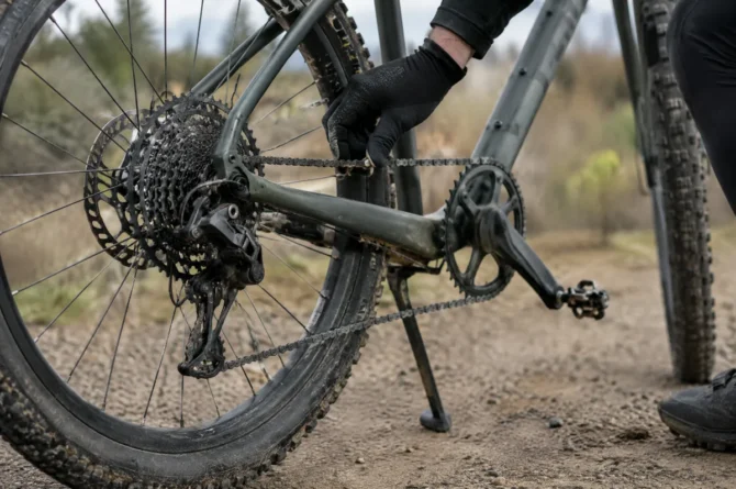 Detalhe da transmissão e do pneu largo de uma bicicleta gravel parada em estrada de terra