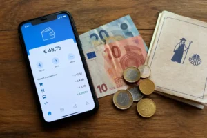 Carteira digital no celular ao lado de euros: Wise, Nomad ou dinheiro no Caminho de Santiago